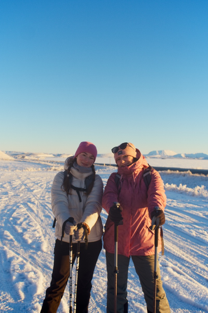 Two hikers standing together in winter light.